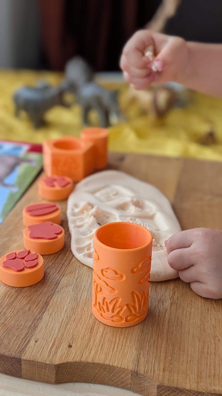 Copil se joacă cu unelte pentru plastilină joacă bună — roller cu savană, ștampile rotunde și plastilină cu urme, pe masă de lemn